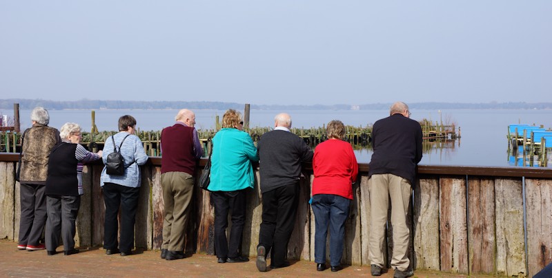 Passanten gucken aus dem Kurpark auf das Meer